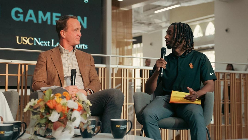 In the Wallis Annenberg Hall Forum, Peyton Manning, left, engages with student Elijah Patterson, right, who holds a mic and asks a question.